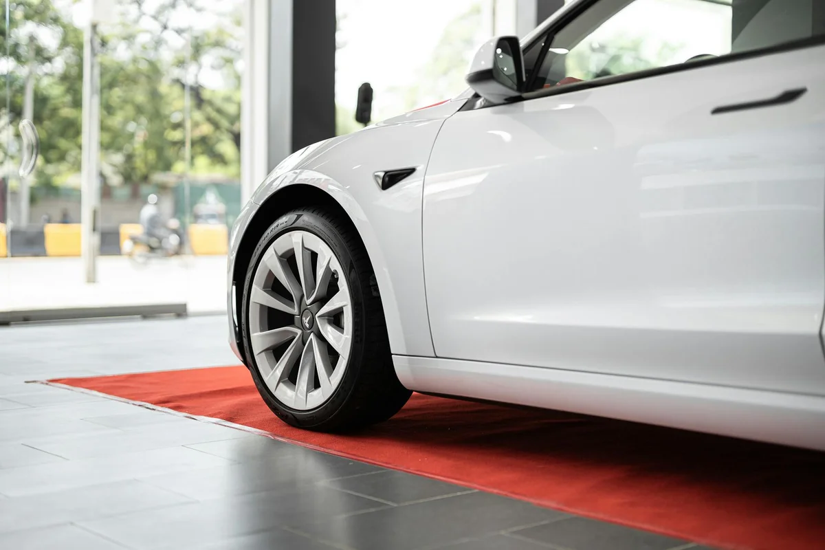Sleek white electric car on display in a modern showroom on a red carpet.