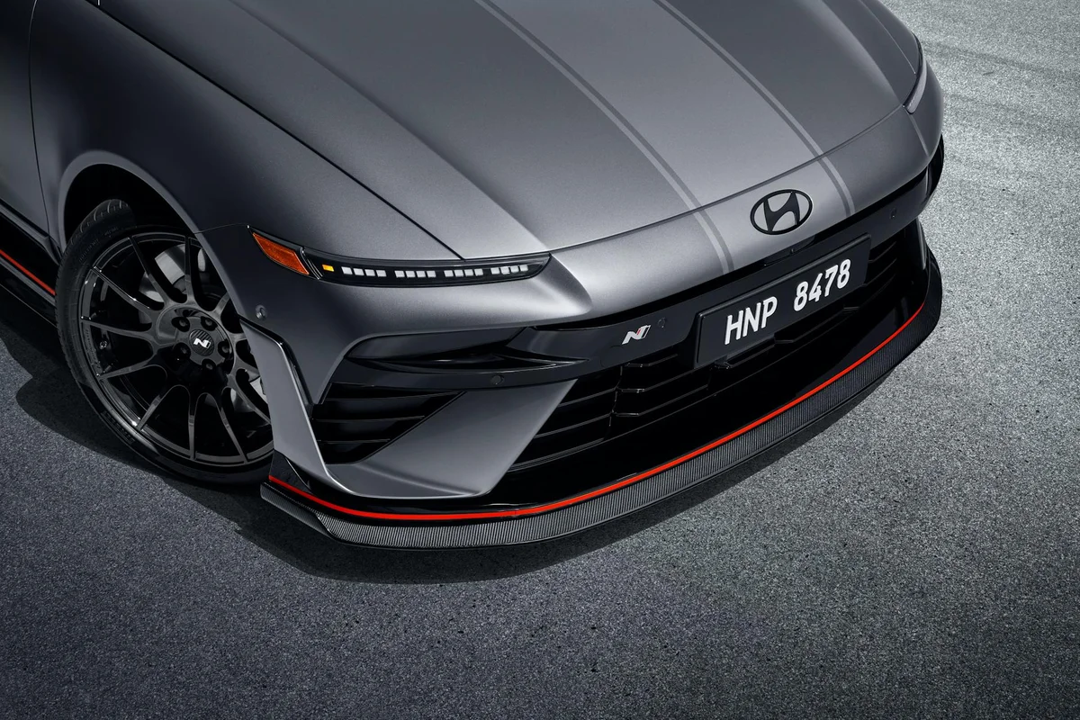 A matte gray car's front with a black grille, red trim, and a license plate reading "HNP 8478".