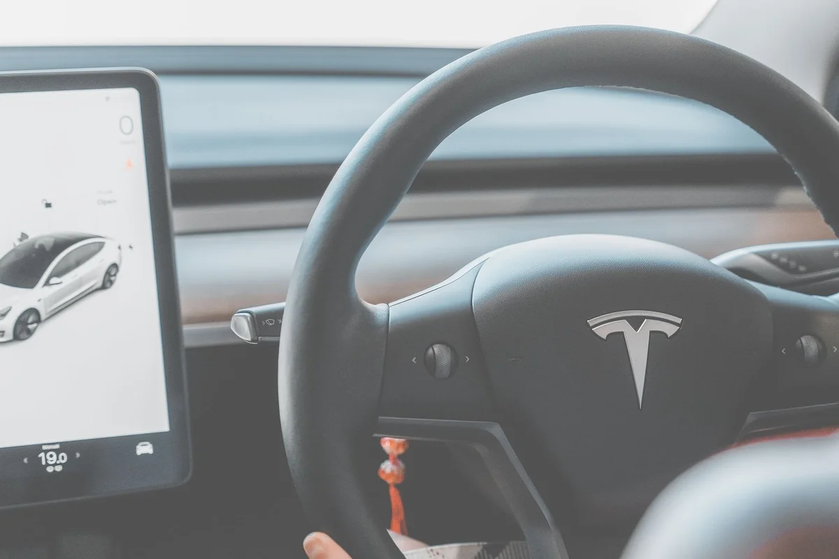 Close-up view of a Tesla electric car steering wheel and digital display, showcasing modern automotive design.