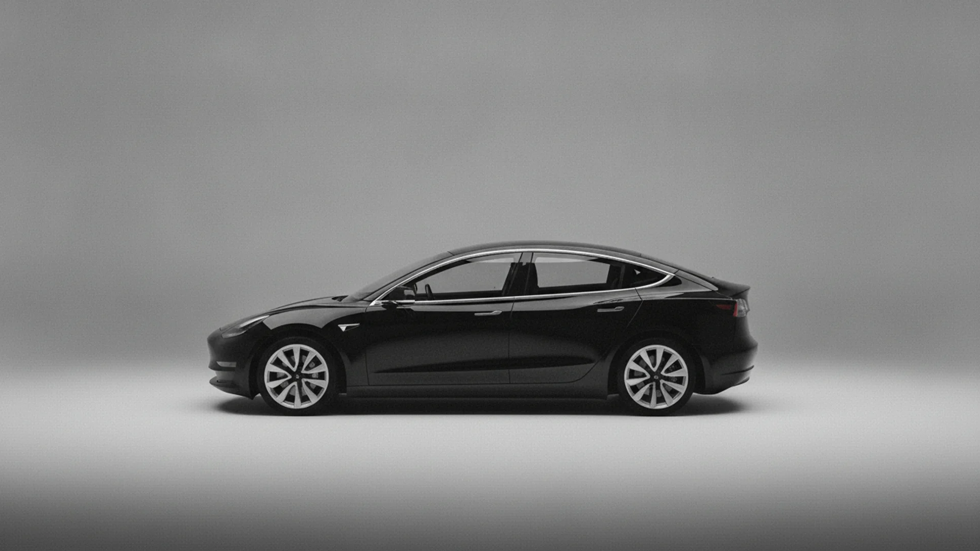 A black Tesla Model 3 is parked facing right on a light gray surface with a matching gray background.