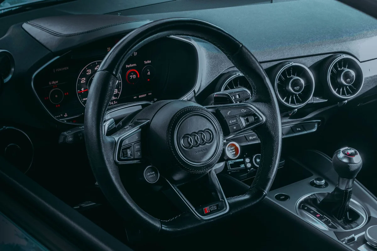 Close-up of an Audi car interior highlighting the steering wheel and dashboard.