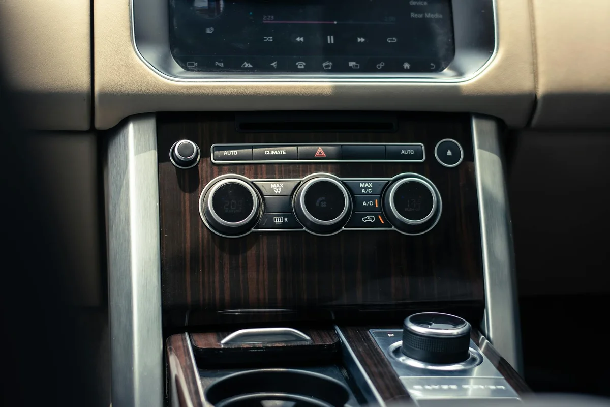 Luxury car dashboard interior featuring climate and audio controls, sleek design.