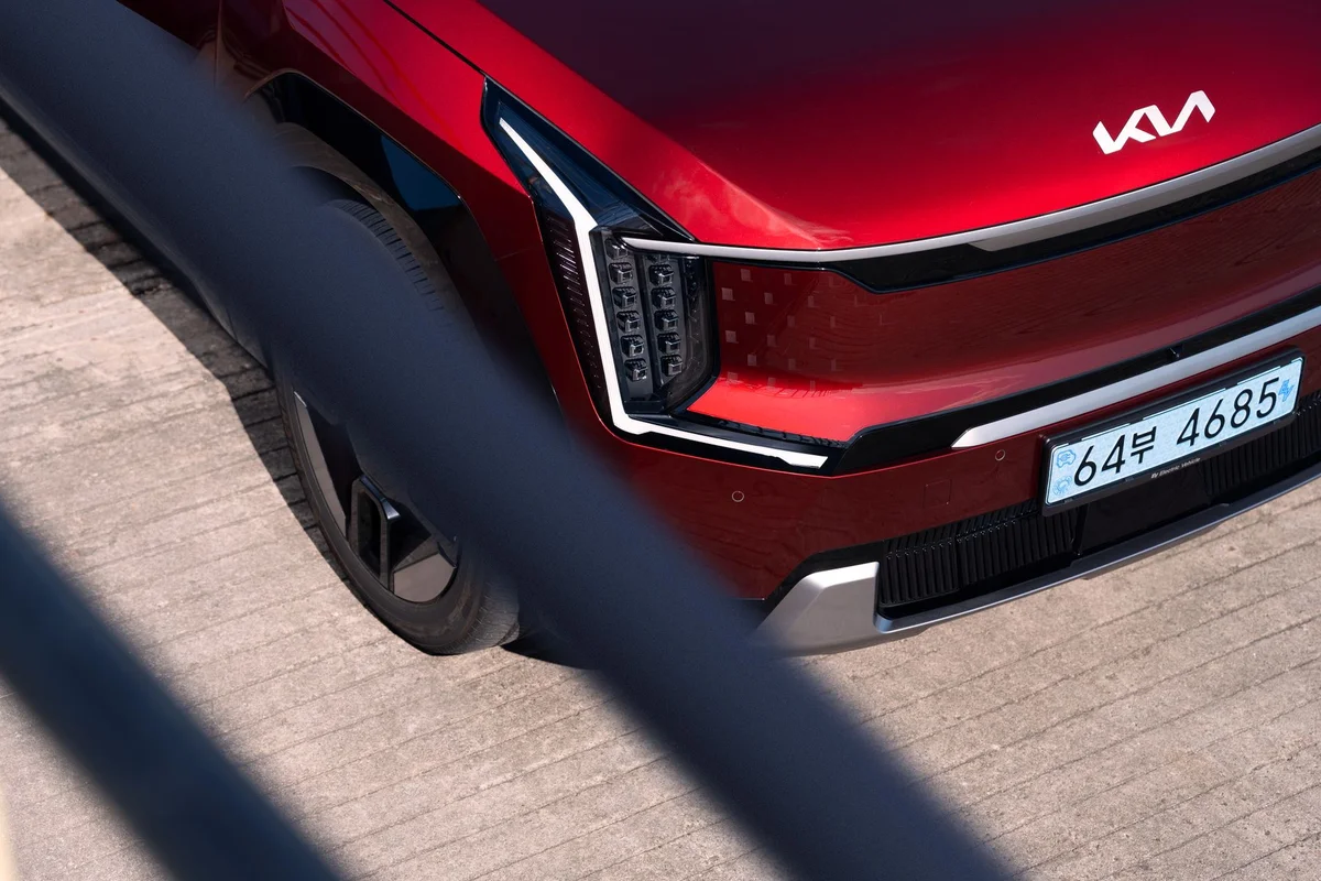 Close-up of a red Kia EV9 electric SUV on a concrete surface, showcasing the front design.