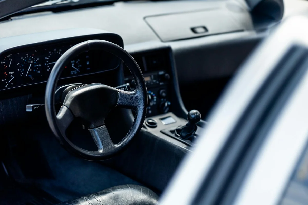 Interior view of a vintage car showing steering wheel and dashboard. Ideal for automotive themes.