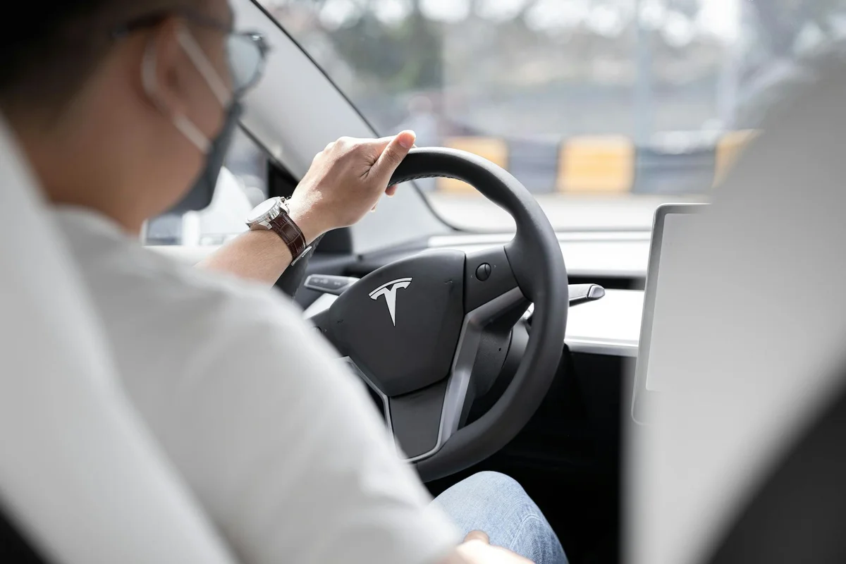 A car's dashboard display shows a green-lit circular screen with a white car icon and a red warning triangle.