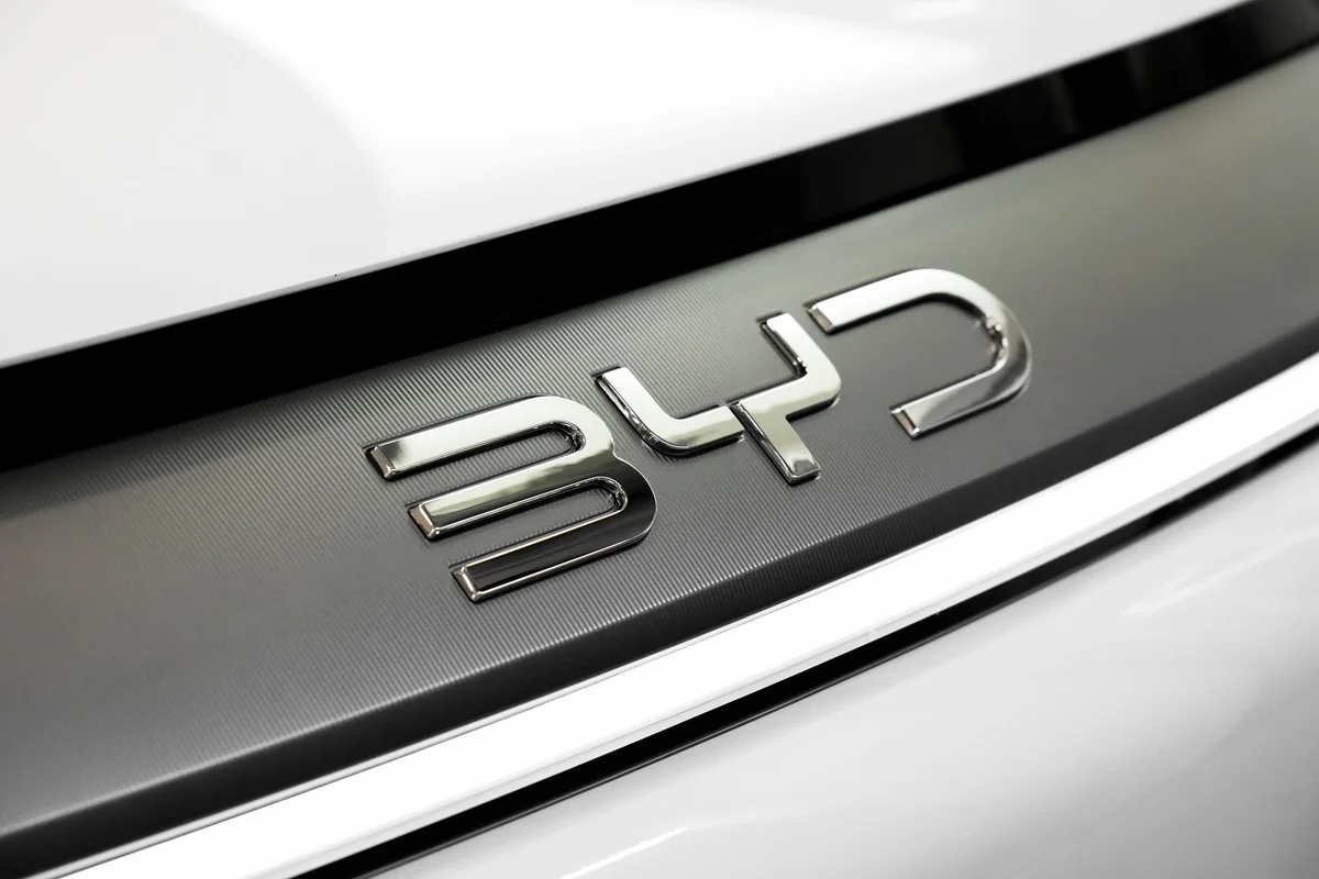 Detailed close-up of the chrome BYD logo on a car, showcasing sleek automotive branding.