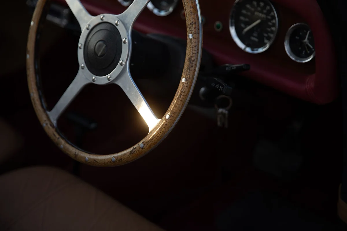 Close-up of a vintage car's wooden steering wheel, showcasing classic design.