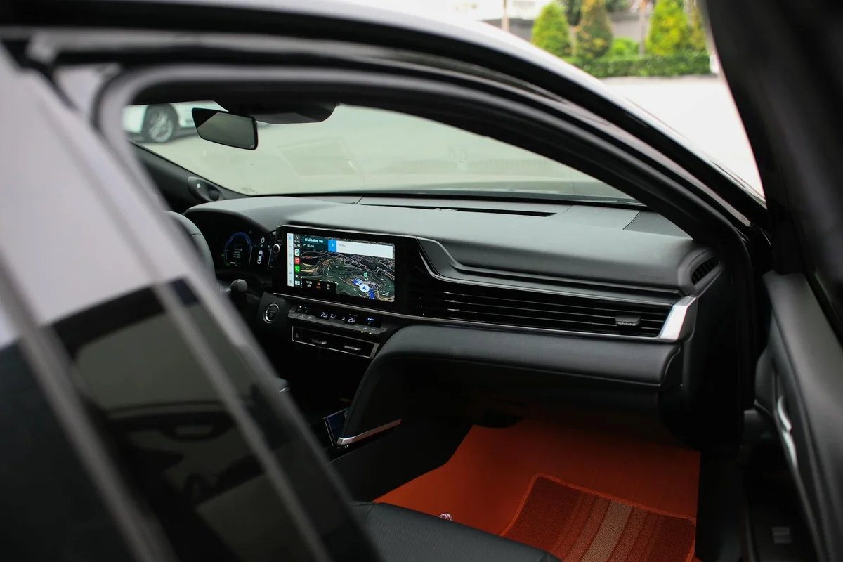 The interior of a car with a navigation screen displaying a map, and orange floor mats.