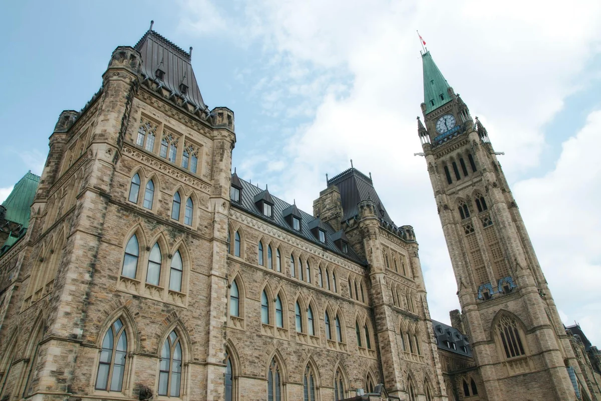 A view of the historical Parliament Hill building in Ottawa against a clear sky.