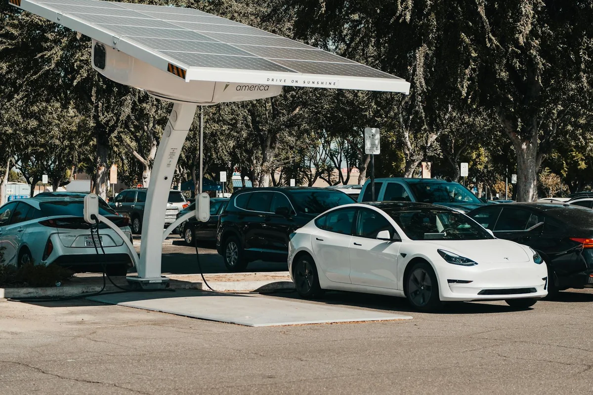 Electric car parked at a solar charging station outdoors, highlighting renewable energy and innovation.