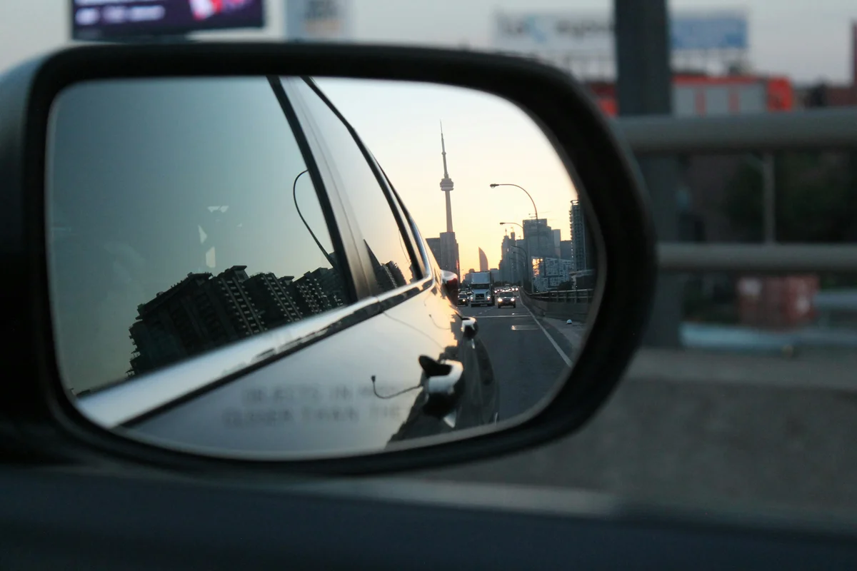 City skyline reflected in a car's side mirror