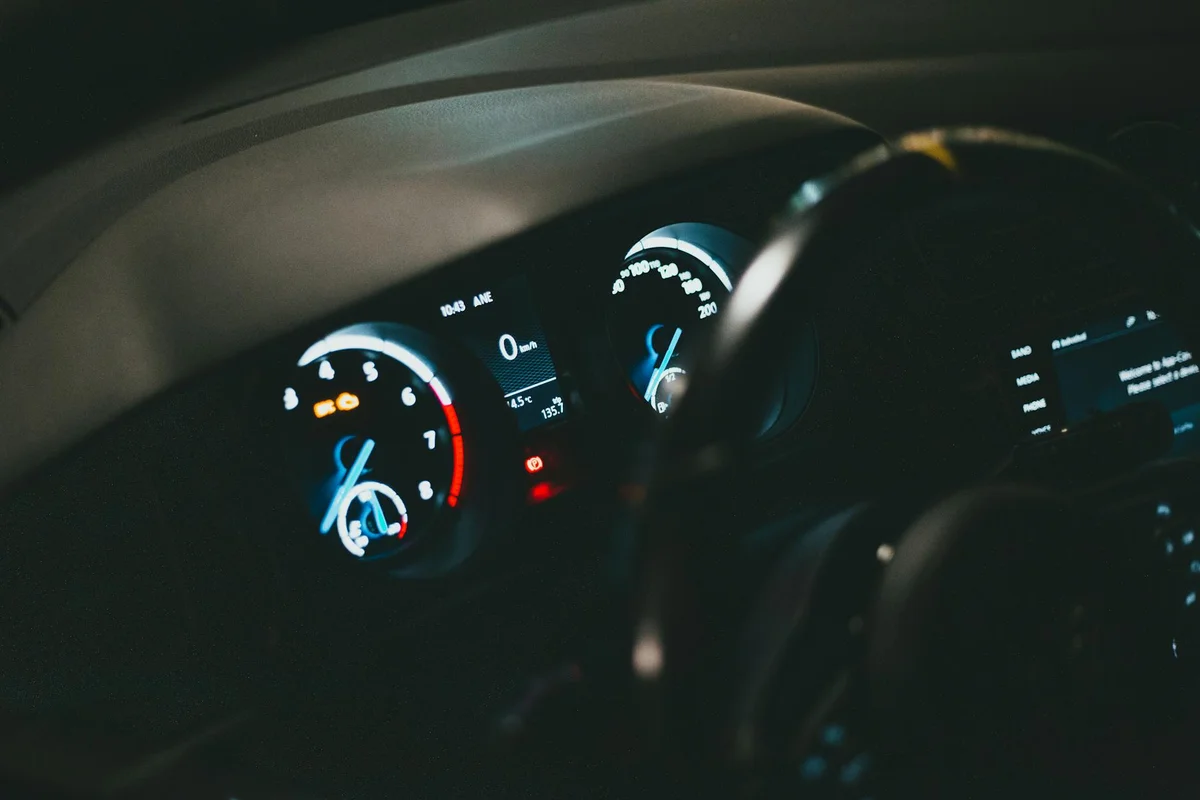 Detailed view of an illuminated car dashboard with speedometer and odometer visible.