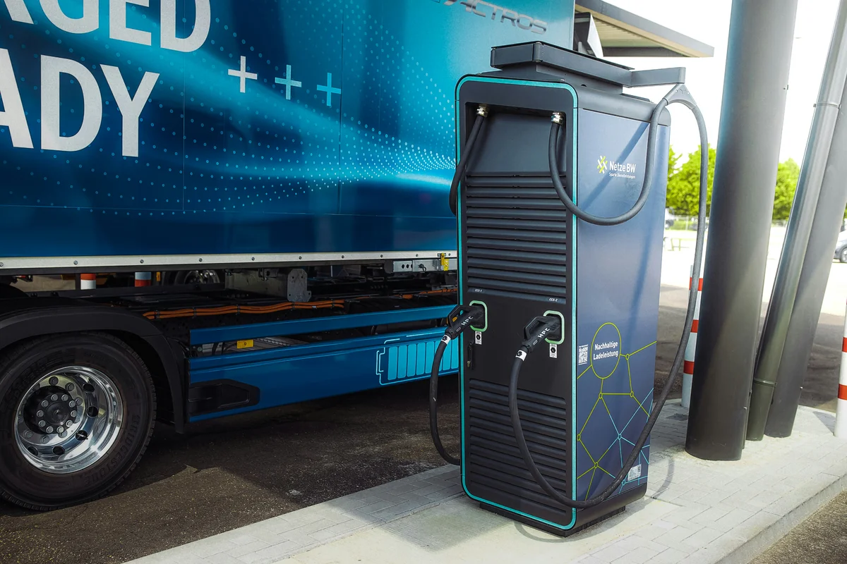 A black and blue charging station with two cables plugged into a blue electric truck.