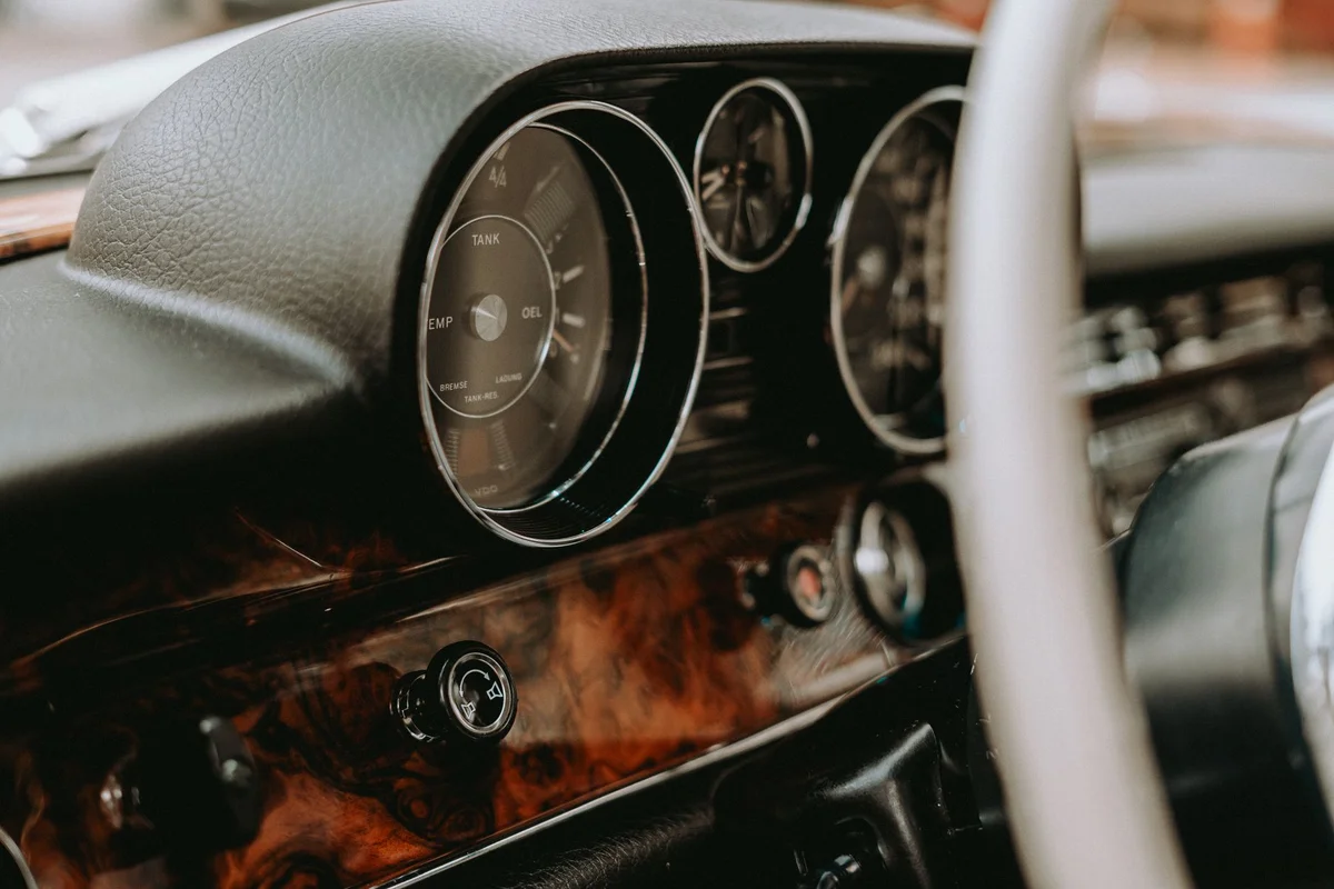 Close-up of a vintage car dashboard showcasing classic gauges and a retro steering wheel.
