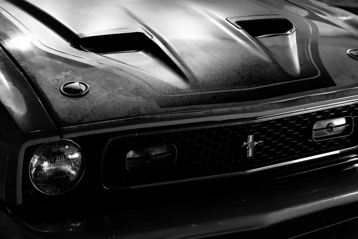 Monochrome image of a Ford Mustang's front grille and headlight with a classic vintage look.