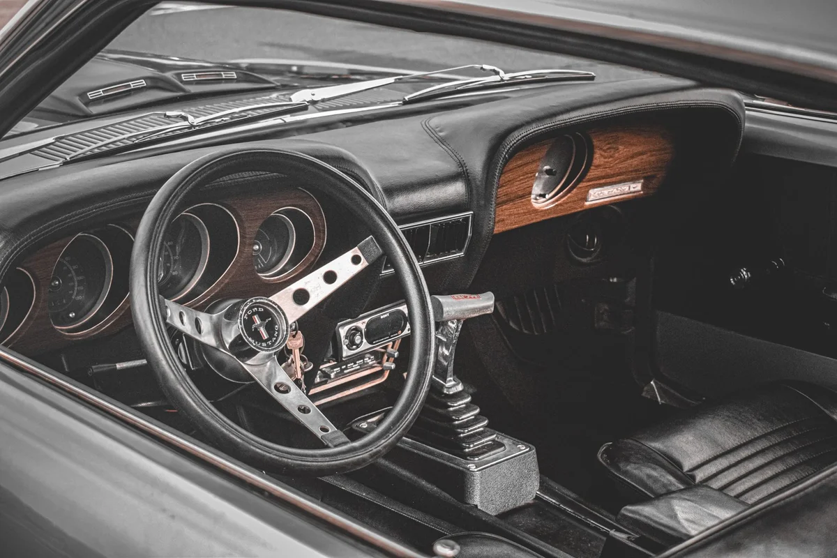 Detailed view of a classic Ford Mustang's interior with a vintage steering wheel.