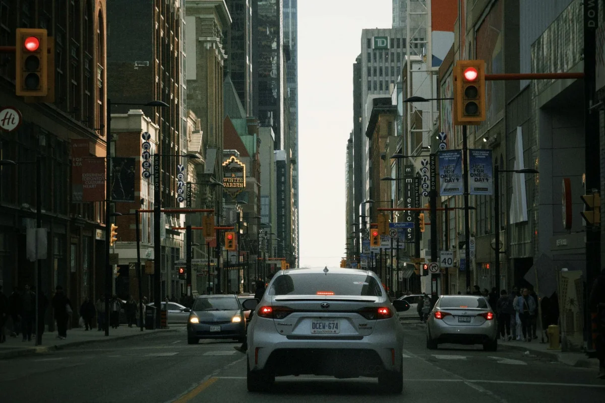 A bustling street view of downtown Toronto with cars and urban buildings in the background.