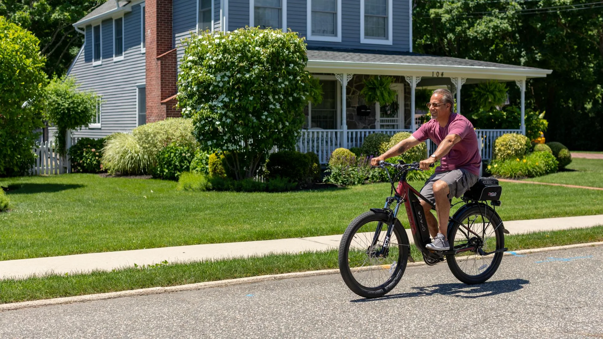 A man enjoys a sunny ride on his electric bike in a suburban neighborhood.