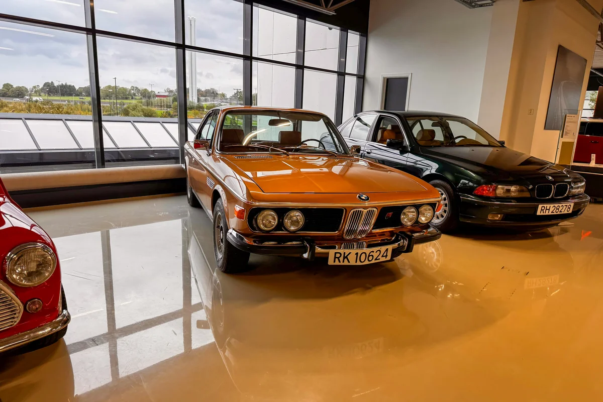 Orange vintage car parked indoors with other cars
