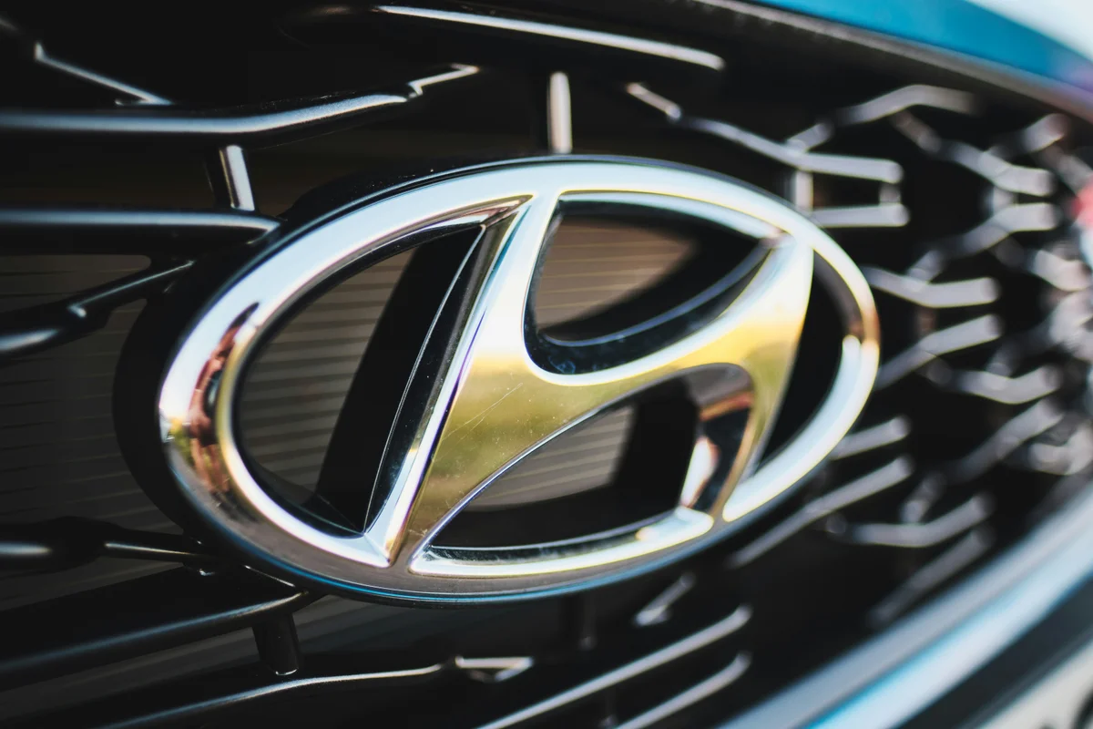 A shiny chrome Hyundai logo is centered on a black car grille with a geometric pattern.
