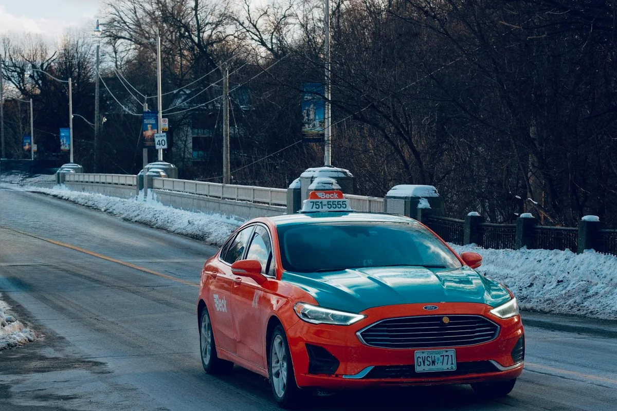 Taxi with distinct livery driving on a snowy bridge in Toronto, capturing the essence of winter travel.