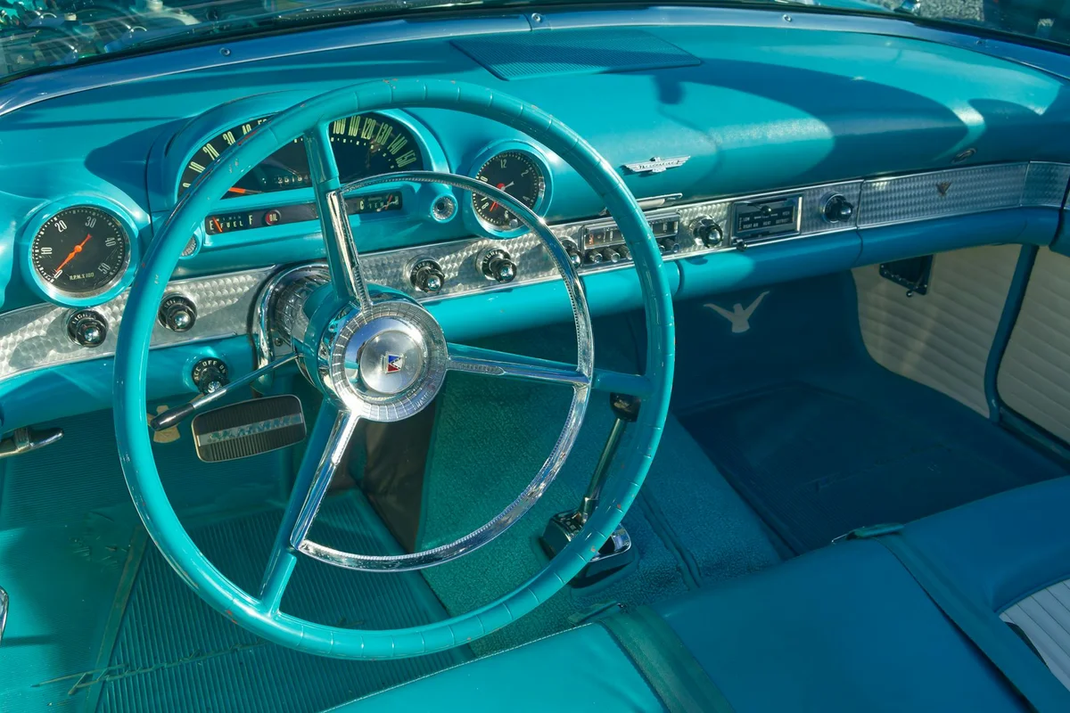 Blue vintage Ford Thunderbird dashboard and steering wheel in focus.