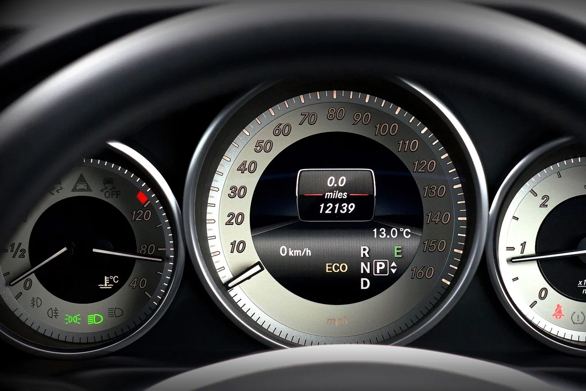 A car dashboard shows a speedometer at 0 mph, with a digital display showing 12139 miles.