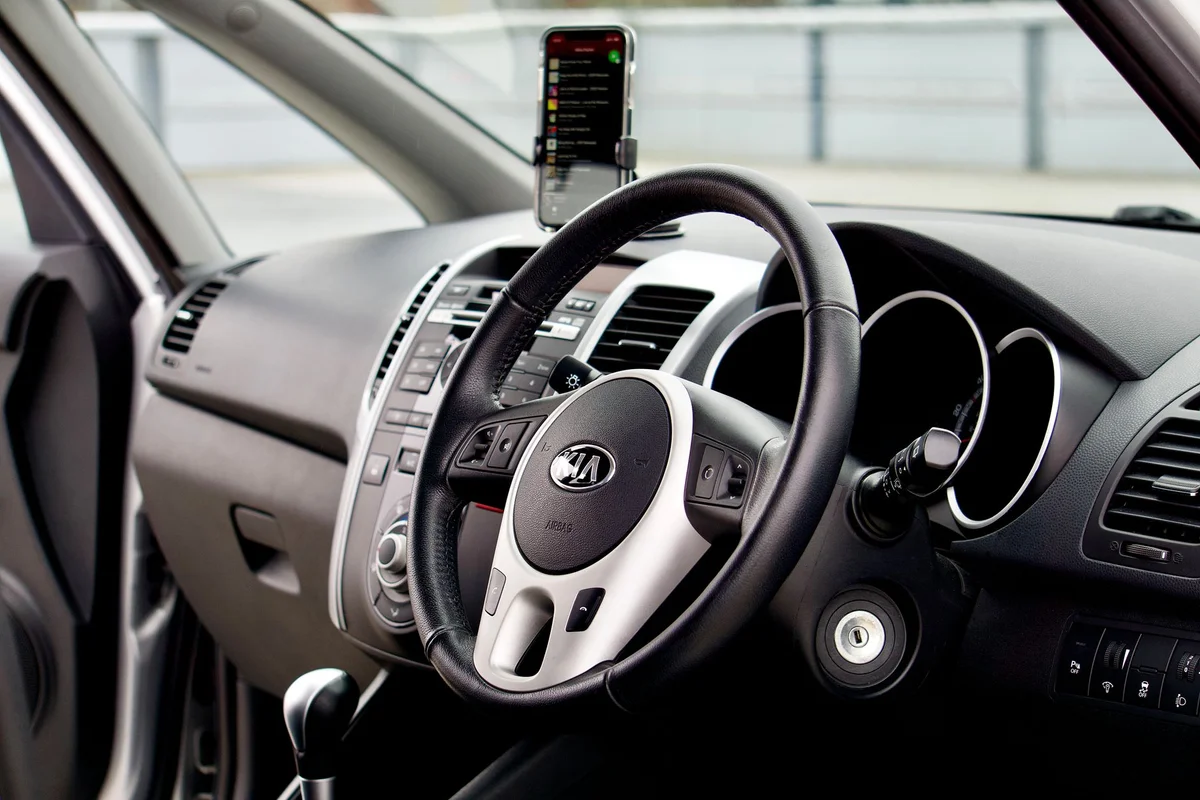 Close-up of a modern car interior featuring a dashboard, steering wheel, and smartphone mount.