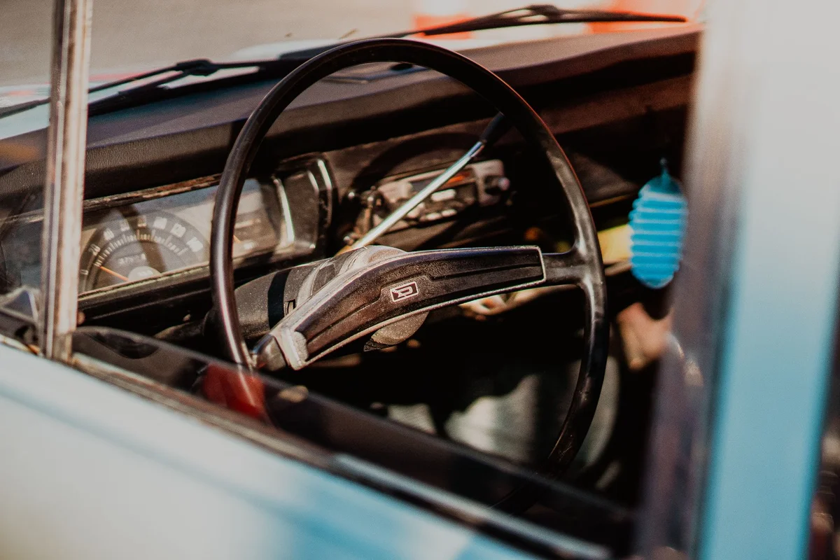 Close-up of a vintage car interior featuring a classic steering wheel and dashboard.