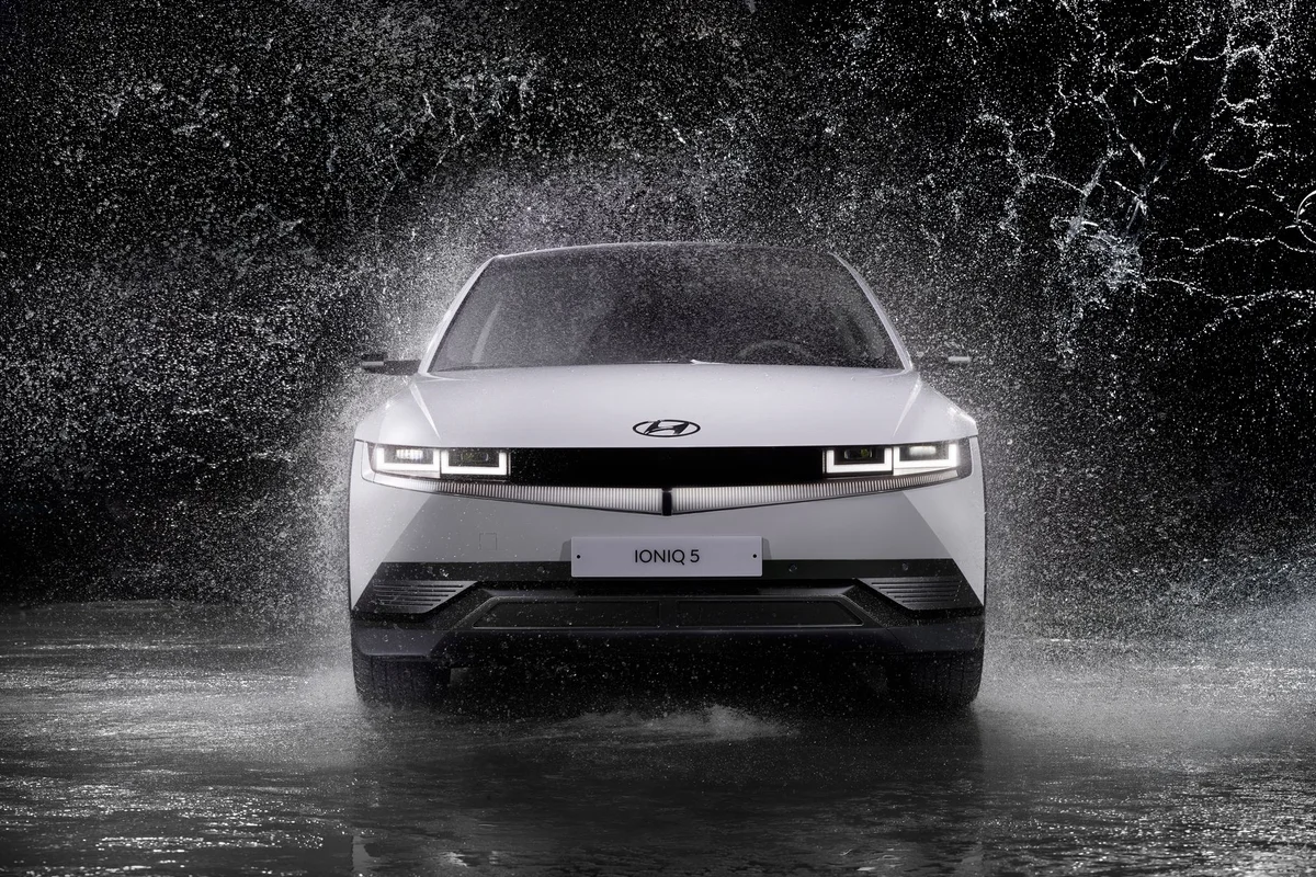 Dynamic front view of a Hyundai Ioniq 5 splashing through rain, captured in black and white.
