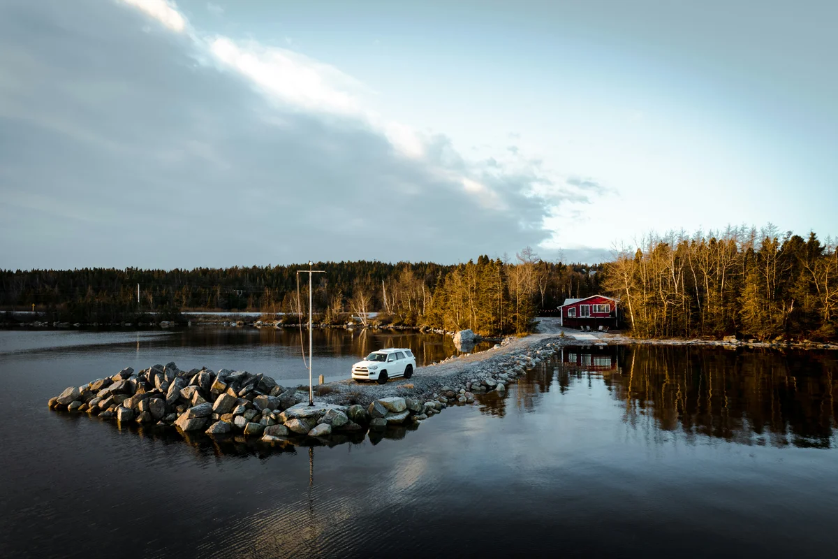 a car is parked on a dock next to a body of water