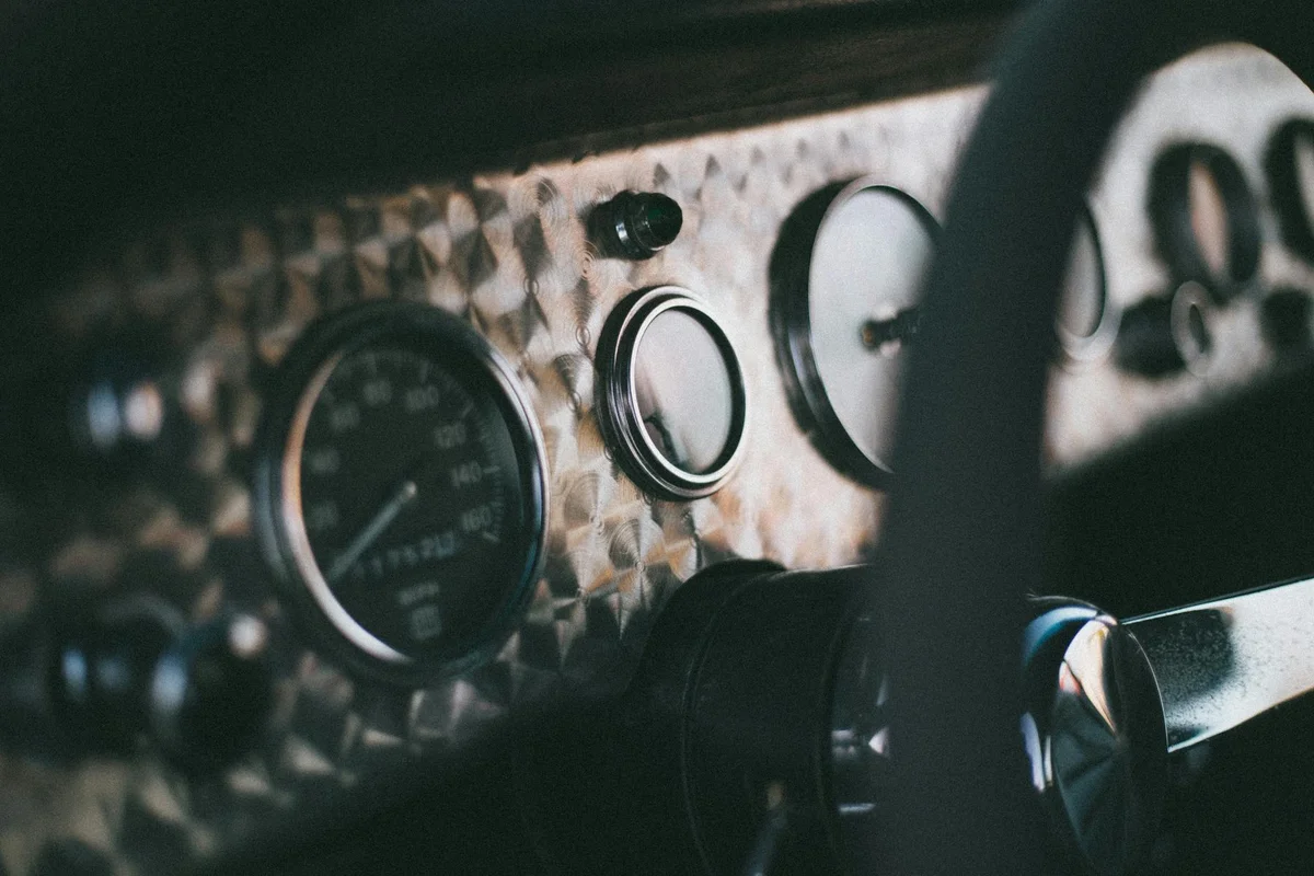 Detailed shot of a vintage car dashboard featuring gauges and speedometer, exuding classic charm.