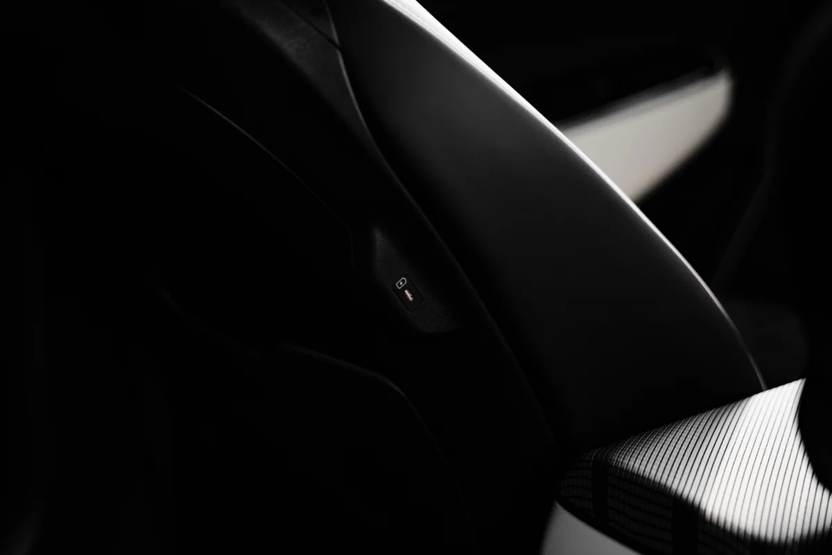 A dark car interior with a small, illuminated orange lock icon on the left side.