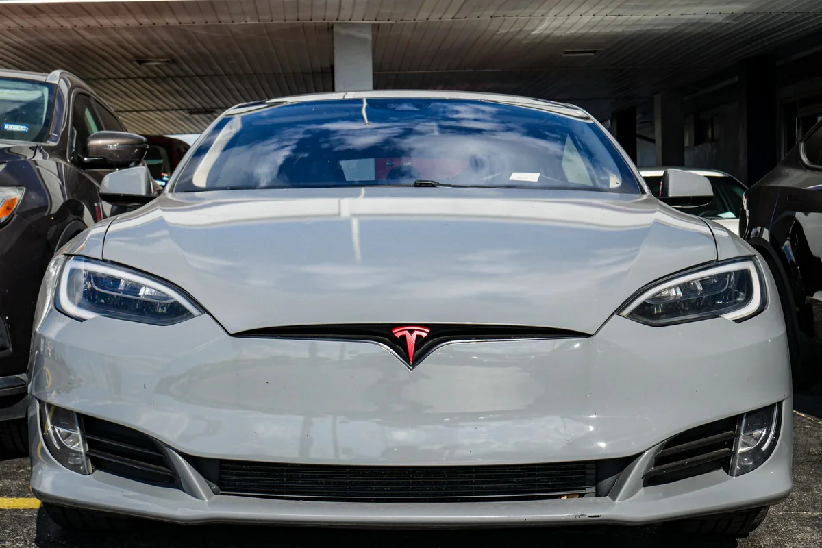 Front view of a Tesla Model S parked in an urban area, highlighting sleek design and modern aesthetics.