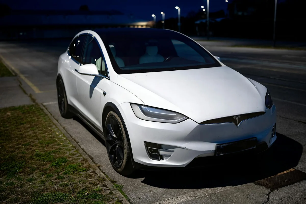 A white electric vehicle parked on an empty street in Garešnica at night.