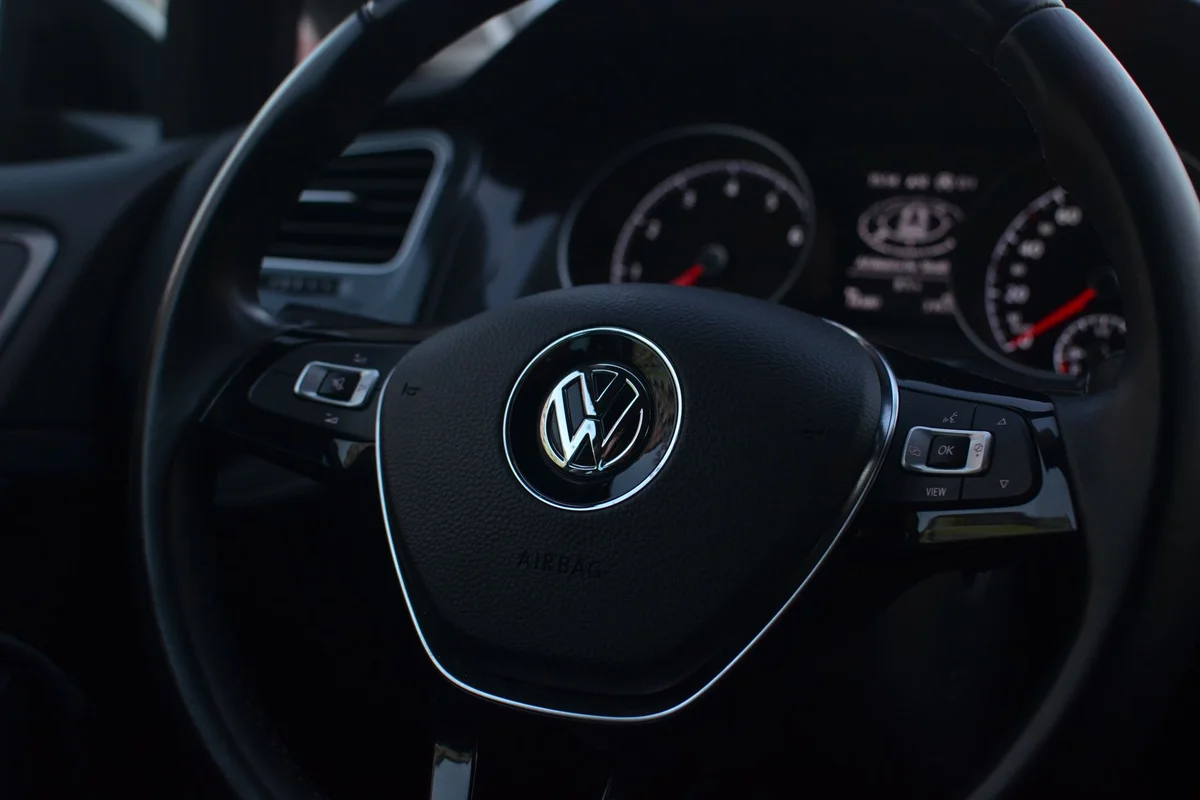 Interior of modern automobile with buttons on steering wheel with panel containing instruments and controls