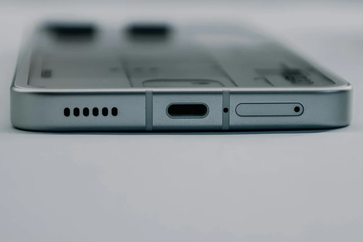 A white USB-A cable with a copper-colored connector lies on a light gray wooden surface.