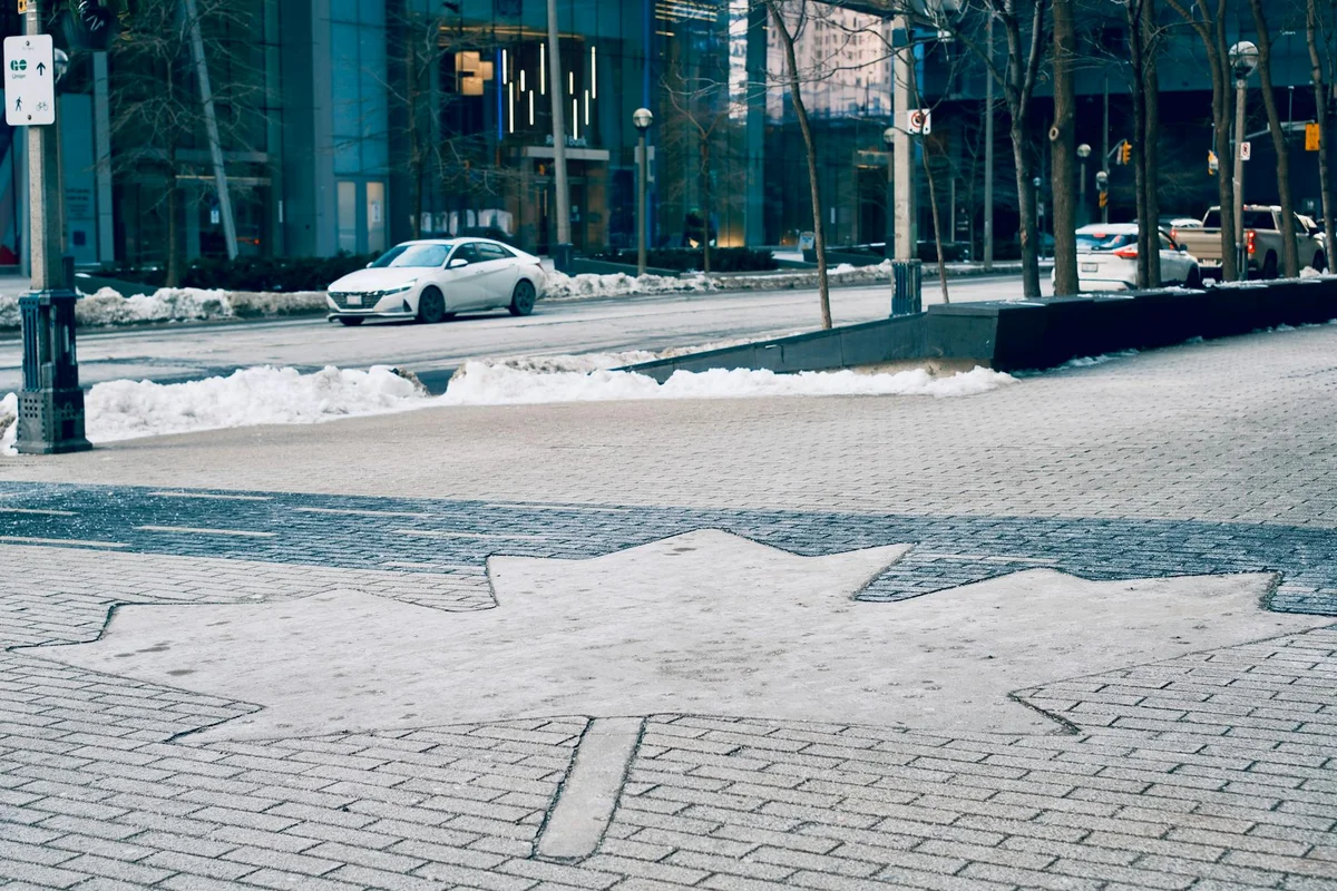 Snow-covered city street in Toronto featuring a maple leaf design on the sidewalk.